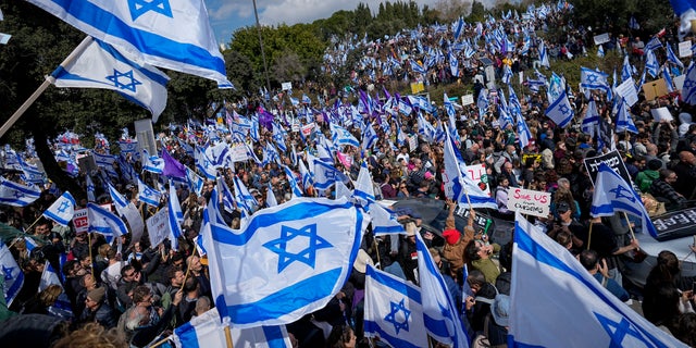 Israelis wave national flags during protest against plans by Prime Minister Benjamin Netanyahu's new government to overhaul the judicial system, outside the Knesset, Israel's parliament, in Jerusalem, Monday, Feb. 13, 2023. Thousands of Israelis protested outside the country's parliament on Monday ahead of a preliminary vote on a bill that would give politicians greater power over appointing judges, part of a judicial overhaul proposed by Prime Minister Benjamin Netanyahu's government. (AP Photo/Ohad Zwigenberg)