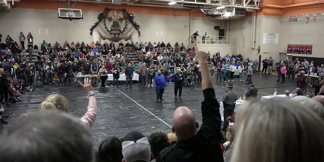 A man raises his hand with a question for East Palestine, Ohio Mayor Trent Conaway, center, during a town hall meeting at East Palestine High School in East Palestine, Ohio, Wednesday, Feb. 15, 2023. The meeting was held to answer questions about the ongoing cleanup from the derailment on Feb, 3, of a Norfolk Southern freight train carrying hazardous material. 