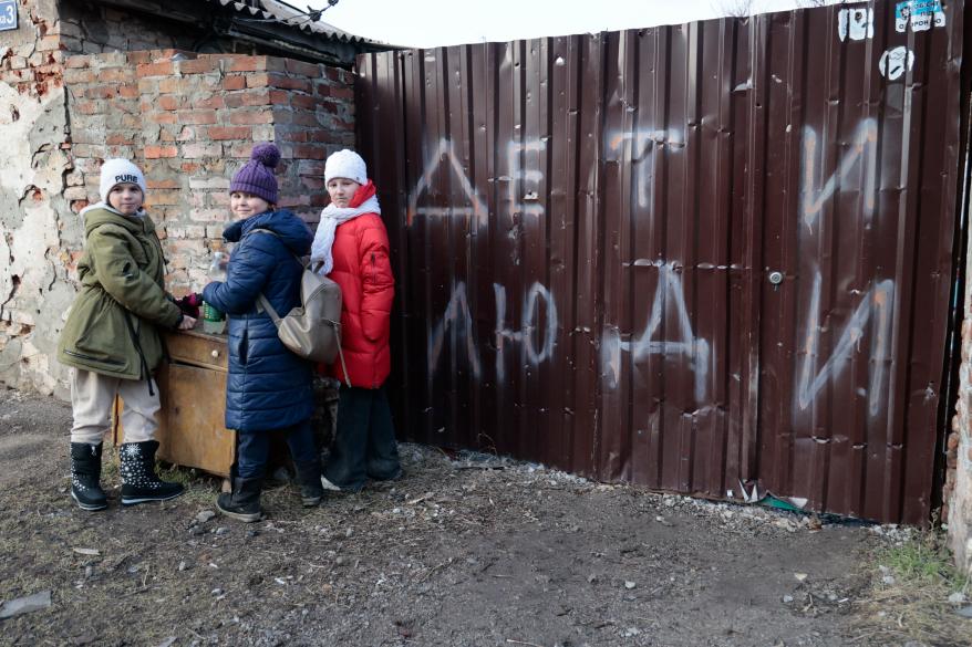 Children standing near a damaged house in Mariupol on February 25, 2023.