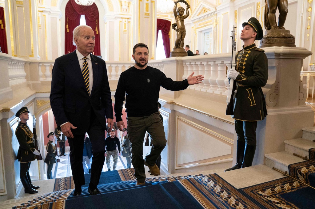 President Joe Biden (L) is led up the stairs by Ukrainian President Volodymyr Zelensky upon his arrival at the Mariinsky Palace in Kyiv on February 20, 2023. - US President Joe Biden promised increased arms deliveries for Ukraine during a surprise visit to Kyiv on Feb. 20, 2023,