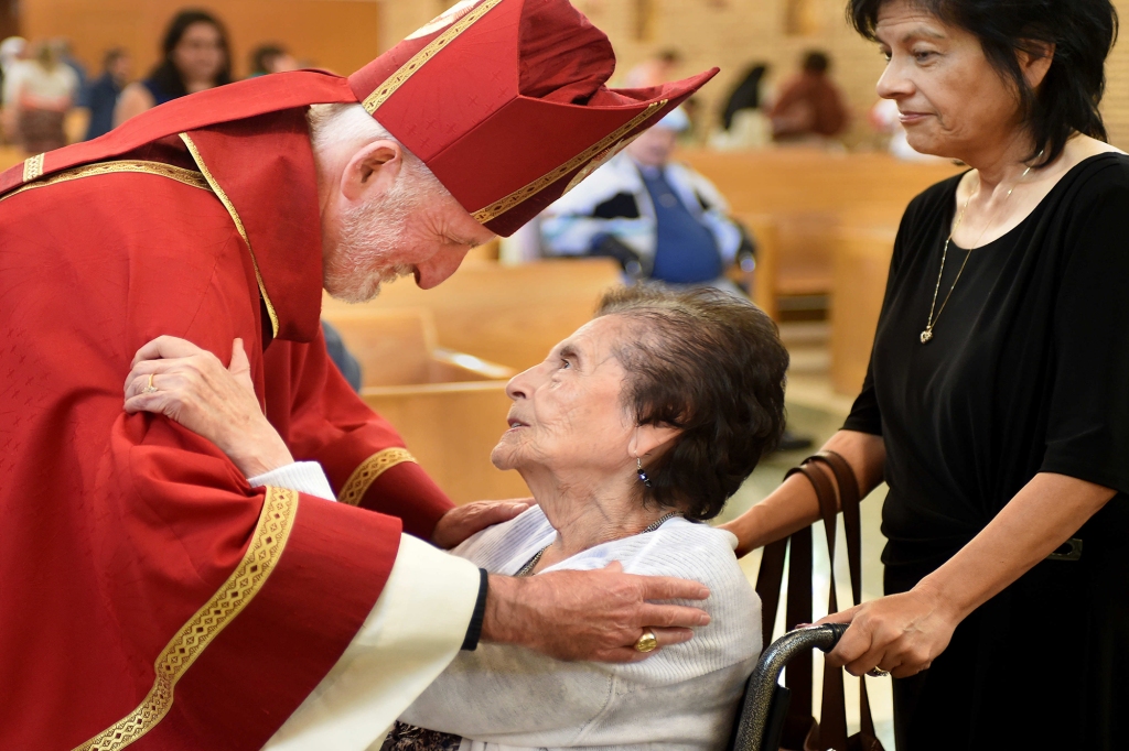 Bishop O'Connell warmly embraces a woman during a service for for the elderly, disabled and those nearing the end of life on June 1, 2016.