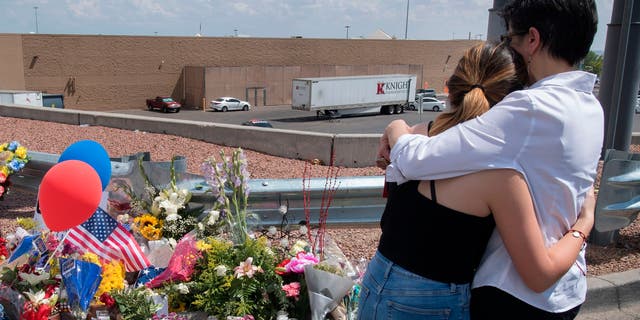 People hug beside a makeshift memorial outside the Cielo Vista Mall Wal-Mart where a shooting left 23 people dead in El Paso, Texas. 