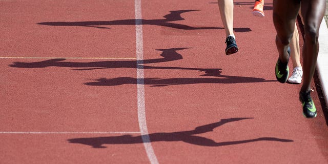 Shadows of the runners of the final over a mile are emerging on the running track.