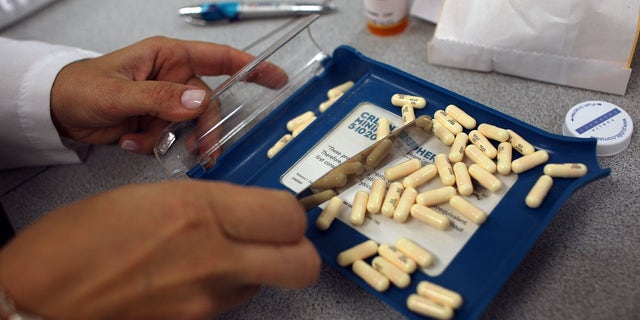 A pharmacy manager counts out the correct number of antibiotic pills to fill a prescription. 