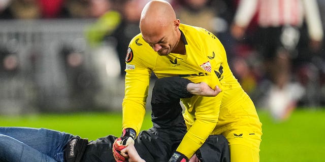 Marko Dmitrović of Sevilla FC fights with a spectator who ran onto the field during a UEFA Europa League knockout round playoff match between PSV and Sevilla FC at the Philips Stadion Feb. 23, 2023, in Eindhoven, Netherlands.