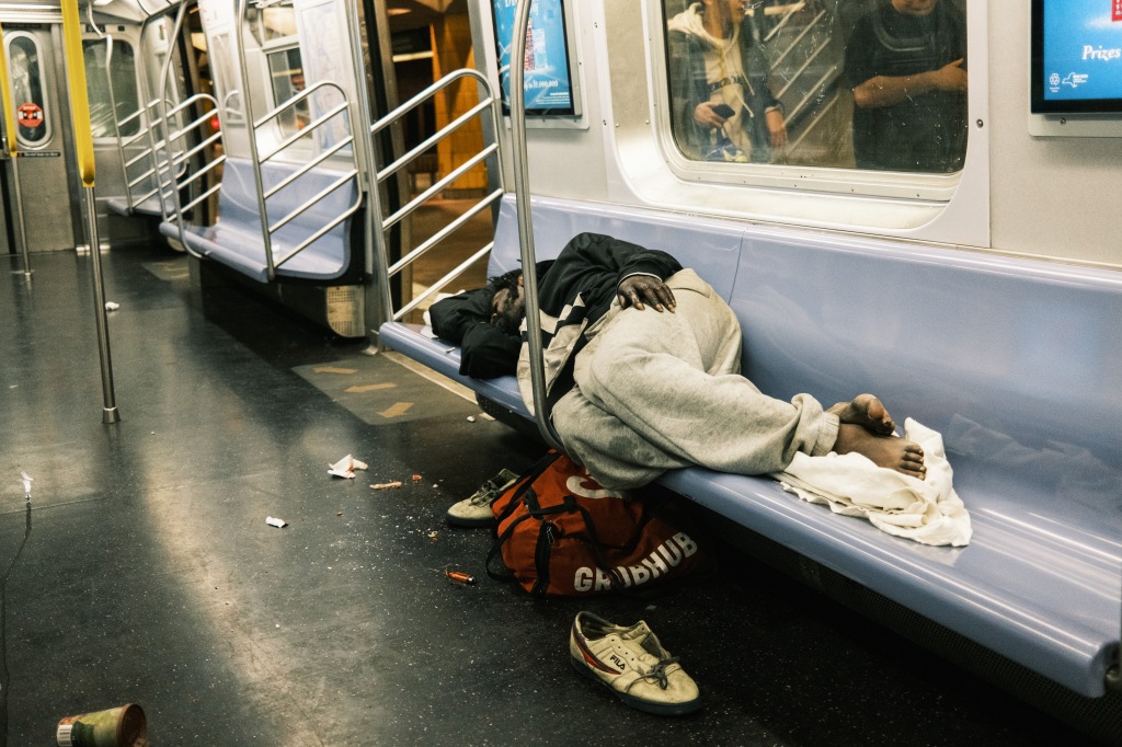 A homeless man sleeps in the Jamaica Avenue J train subway station in Manhattan. 