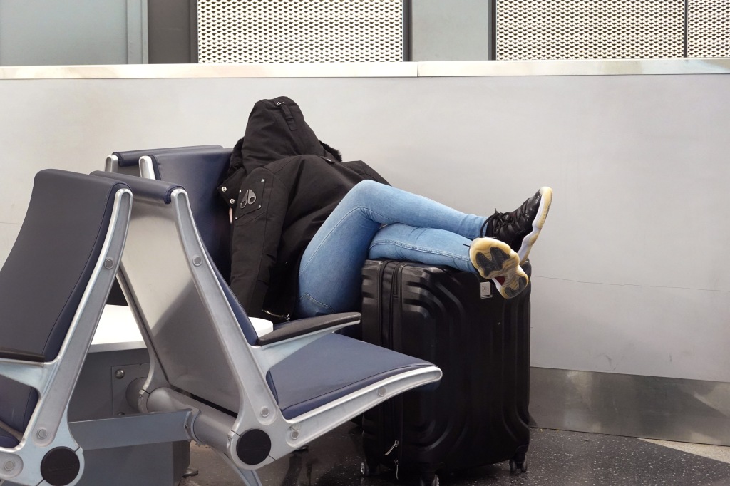 A picture of a woman sleeping at the airport.