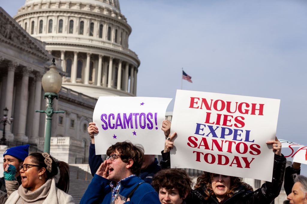 Protsecutors wield signs against Santos outside the U.S. Capitol.