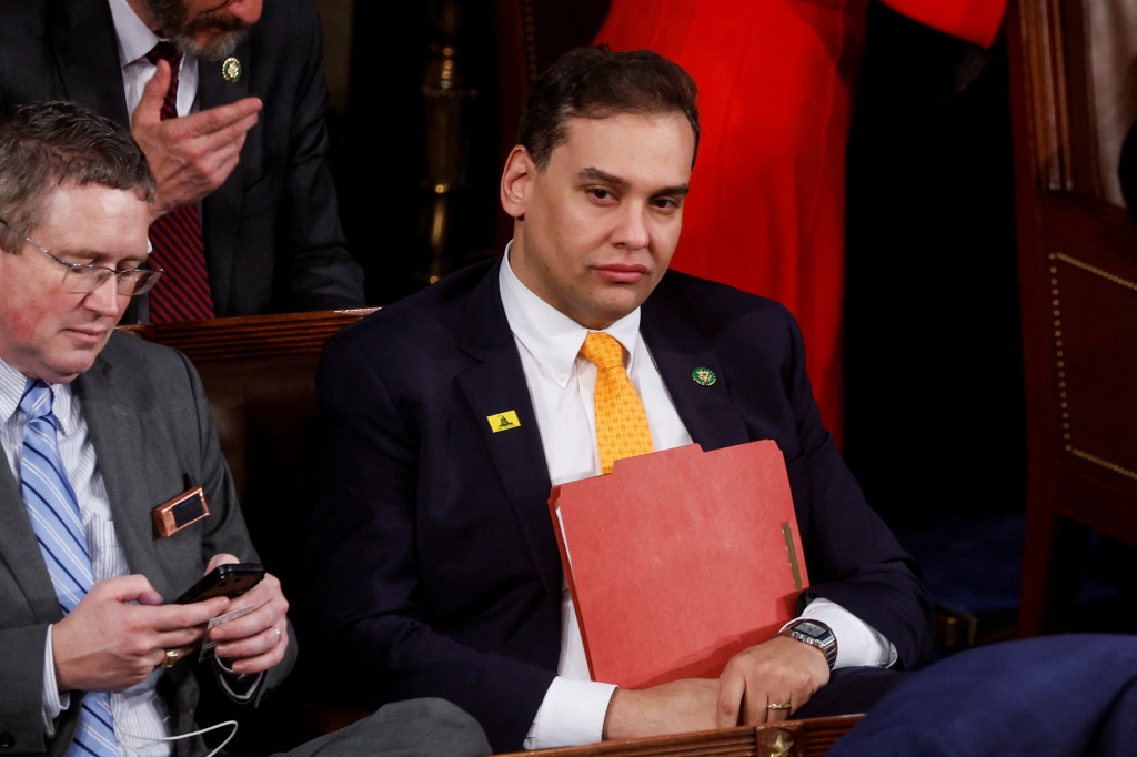 Santos seated at the State of the Union. He is holding a redf older to his chest.