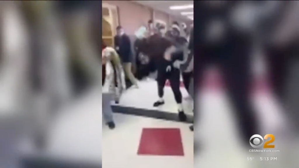 Blurry camera footage of a fight in a high school hallway.