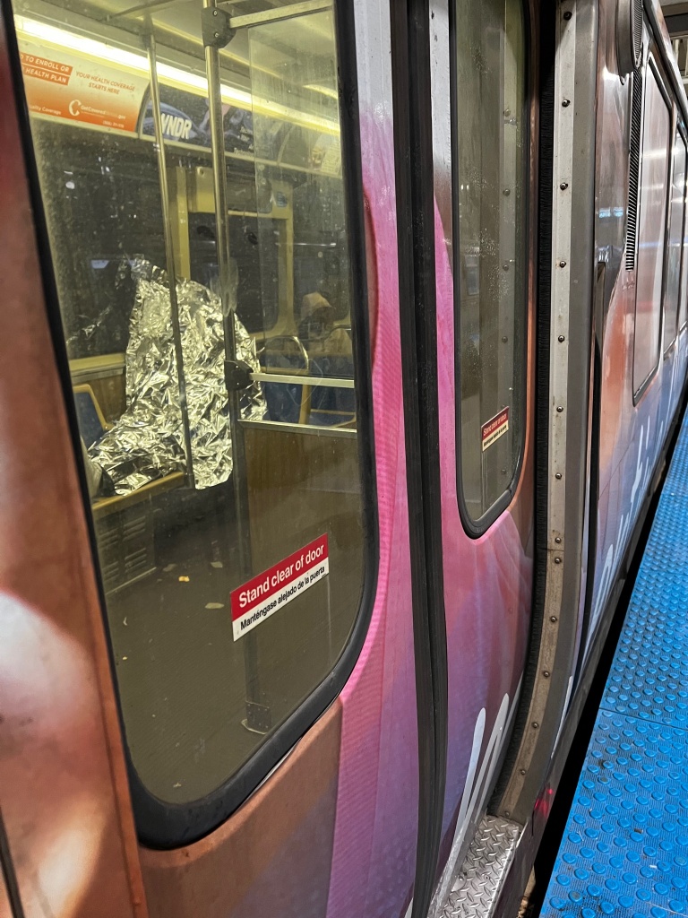 A homeless man covered in foil on a trian.