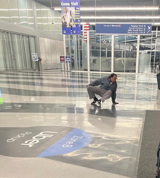 A picture of a homeless man on the floor at an airport.