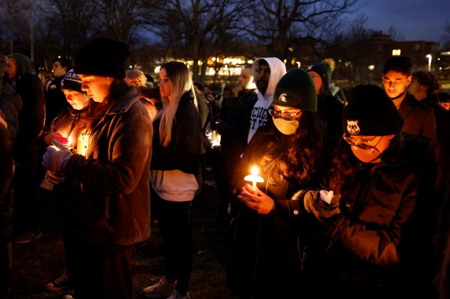 Mourners light candles at vigil for students killed in mass shooting.