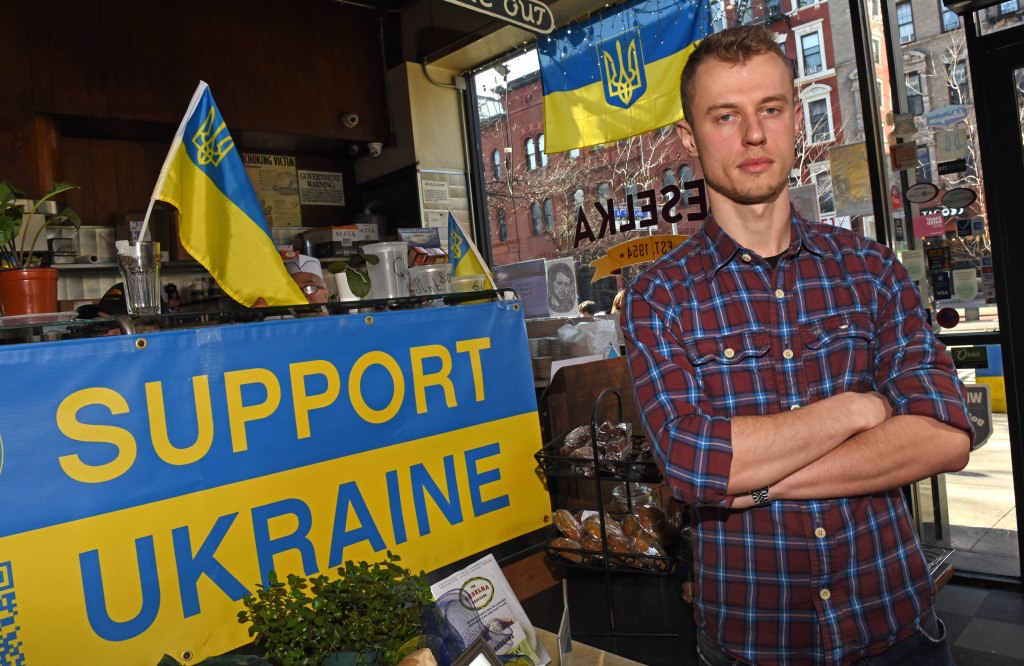 Vitalii Desiatnychenko poses next to a Support Ukraine sign.