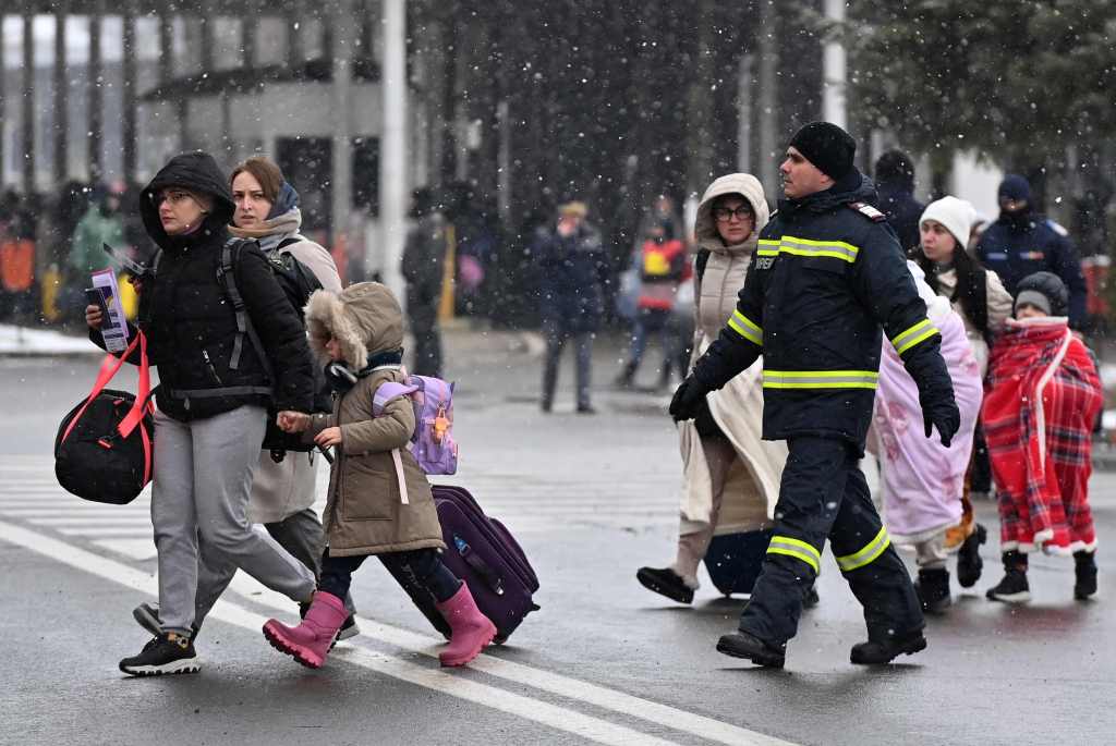 In this file photo taken on March 02, 2022 Refugees coming from Ukraine walk at the Ukrainian-Romanian border in Siret