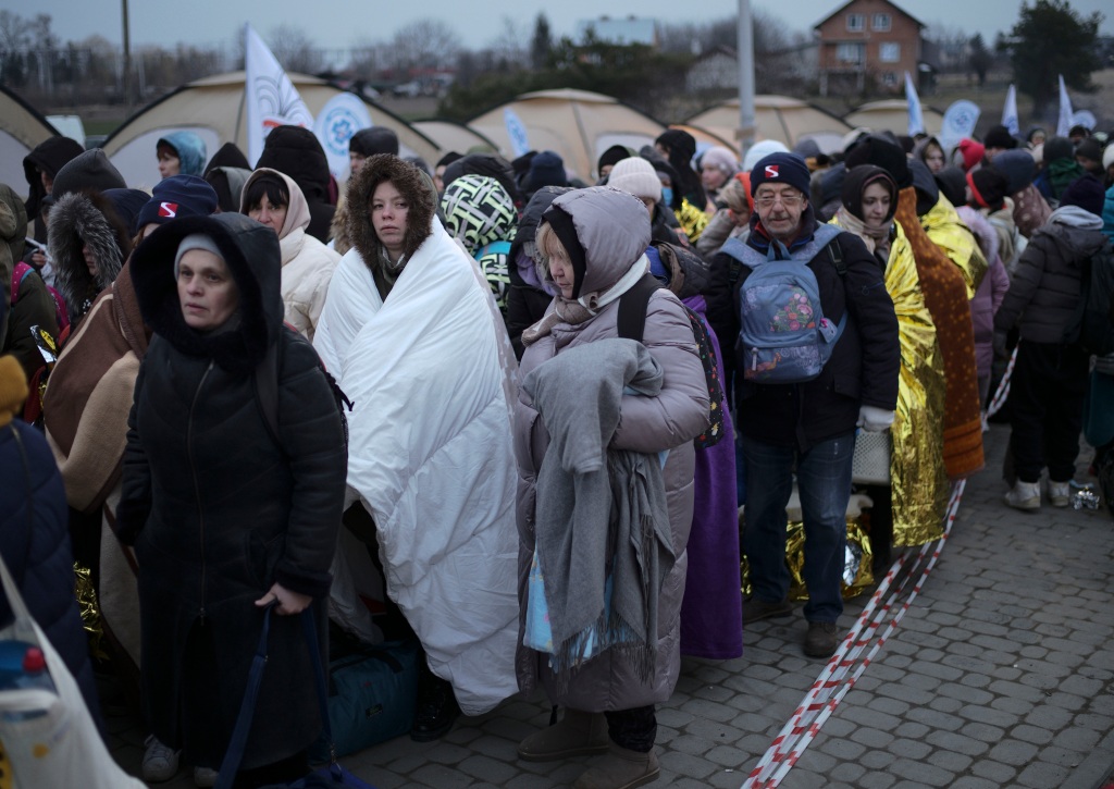 Refugees wait in a crowd for transportation after fleeing from the Ukraine and arriving at the border crossing in Medyka, Poland, March 7, 2022. 