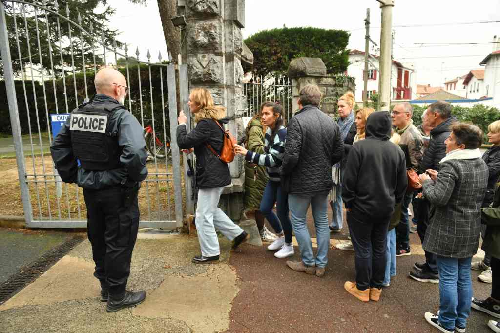 Onlookers gather at the entrance of Saint-Thomas d'Aquin school.