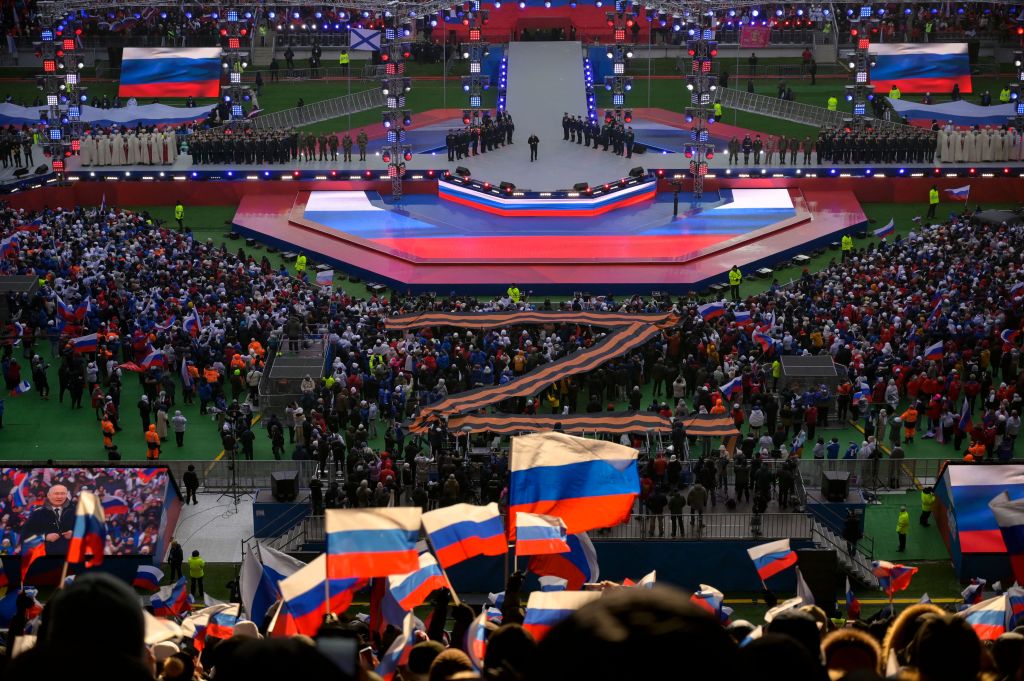 People listen as Russian President Vladimir Putin (center on the stage) gives a speech during a patriotic concert dedicated to the upcoming Defender of the Fatherland Day at the Luzhniki stadium in Moscow on February 22, 2023.