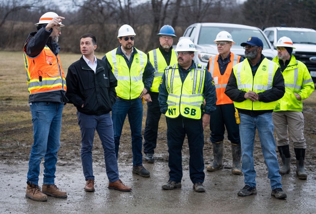 U.S. Secretary of Transportation Pete Buttigieg (2L) visits with Department of Transportation Investigators at the site of the derailment.