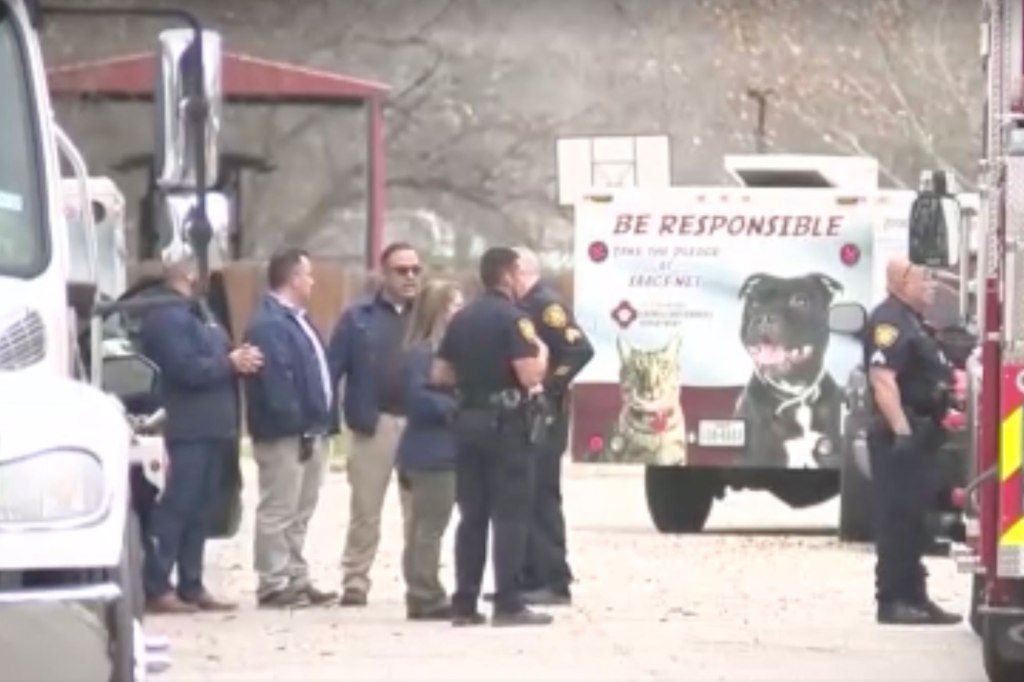 Law enforcement officers stand behind an animal control services van.