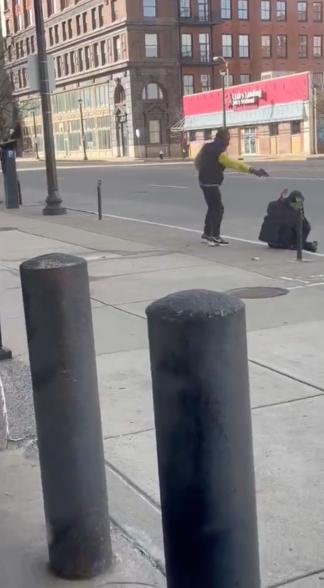 Photo of the shooter pointing the gun at the homeless man, just a few feet from him.