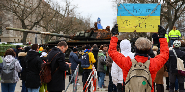 A woman holds a banner saying "Shame on Putin" outside the Russian embassy in Berlin, Germany, on Friday.