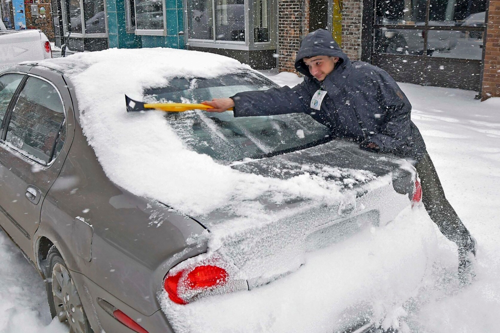 Ayden Ereth brushes snow from his vehicle in downtown Bismarck, N.D., on Tuesday, Feb. 21, 2023.
