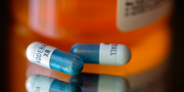 Adderall XR capsules are displayed in front of a medicine bottle.