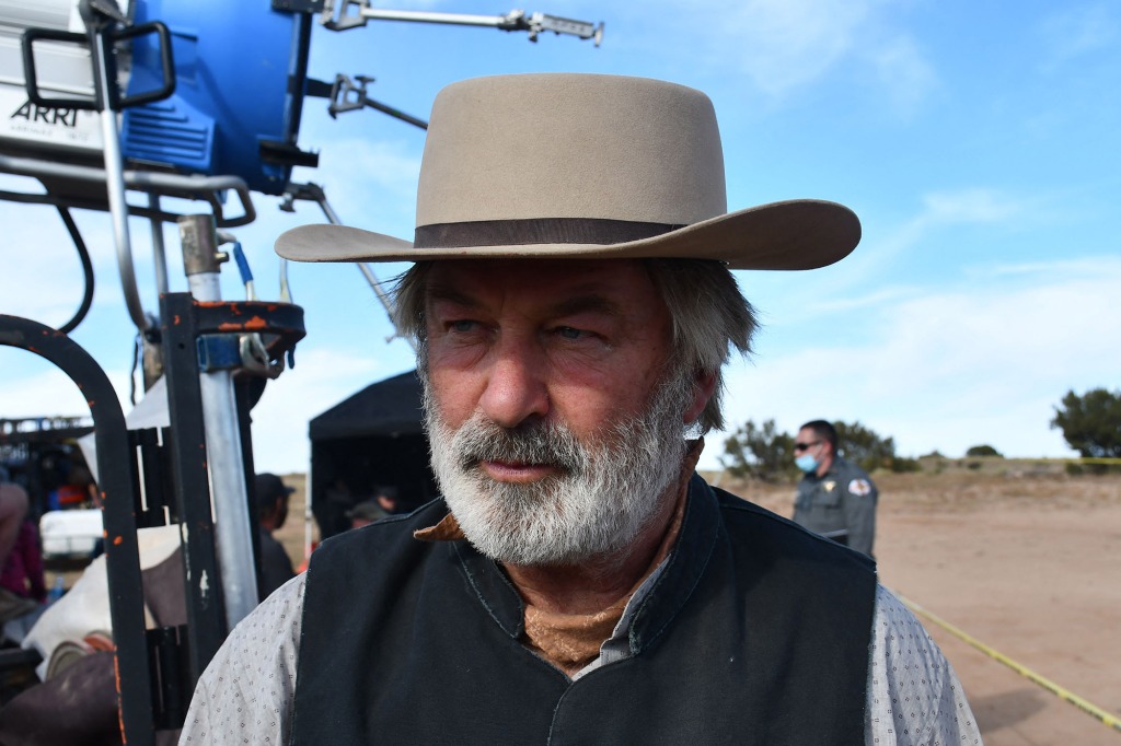 Pictured is Alec  Baldwin on a movie set set dressed as a cowboy.