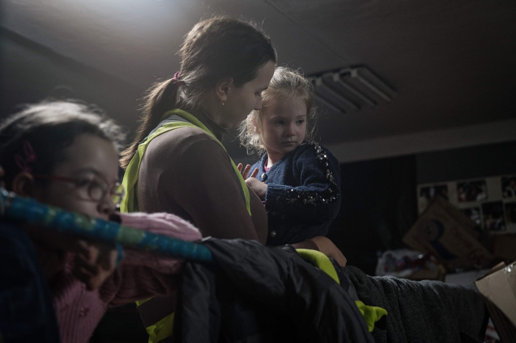 Social worker Tetyana Lemzyakova (2nd R), 23, holds Maria (R), 6, at a humanitarian center in Bakhmut Friday.