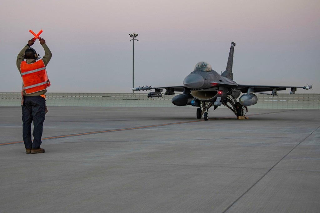 An airman guides an F-16 Fighting Falcon during training at Al-Udeid Air Base, Qatar, Jan. 24, 2022.