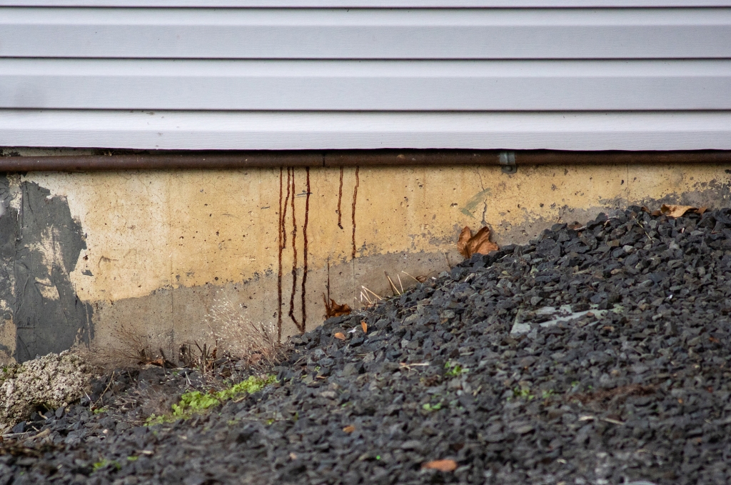 A close-up photo of thin lines of blood dripping down the foundation of the Idaho house.