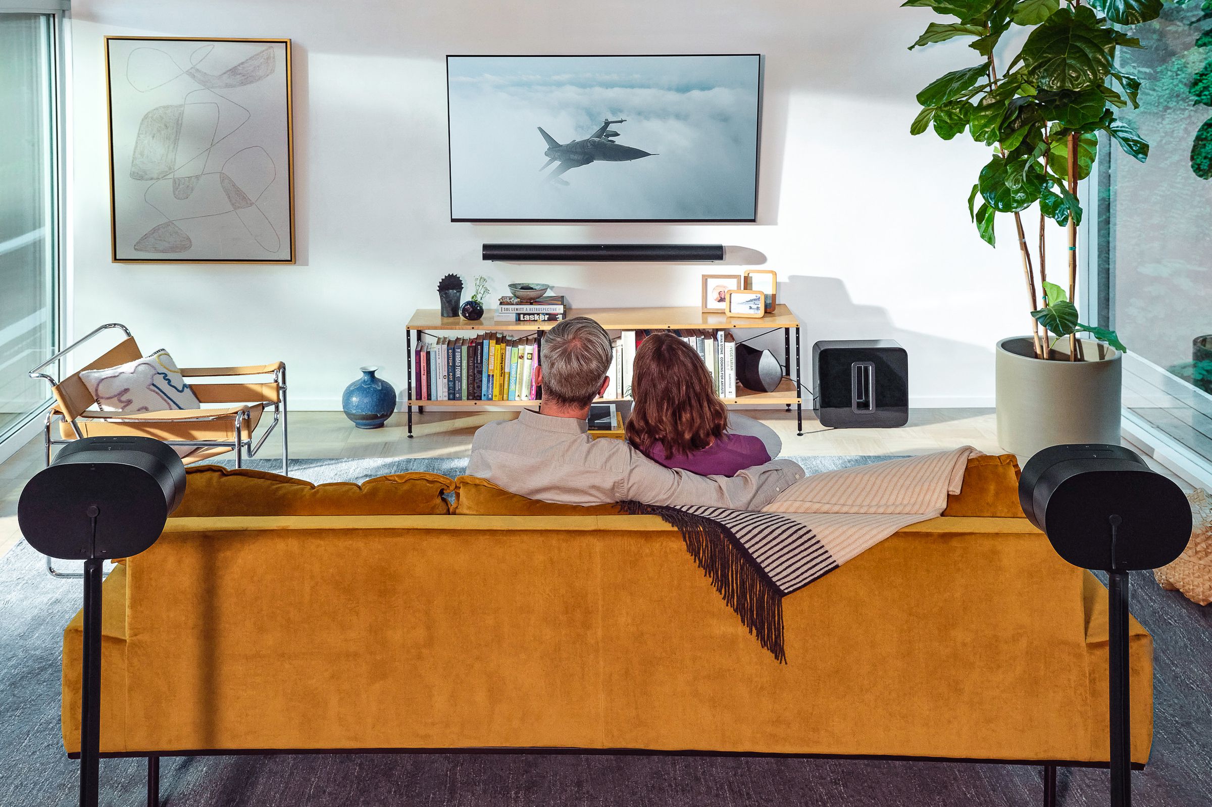 A marketing photo of two Sonos Era 300 speakers being used as rear surround speakers for a Sonos Arc soundbar.