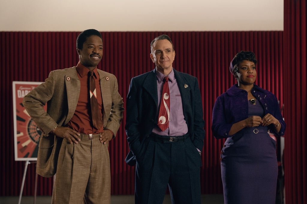 Dewshane Williams, Hank Azaria and Haneefah Wood in a scene from "Hello, World!" They're standing next to each other and looking at someone else; Dewshane has his hands on his hips and Hank's hands are in his pocket. They're all wearing '50s-type outfits (suits for the men and a dress for Haneefah).