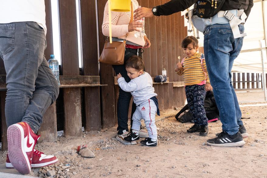 Asylum-seeking migrants from Venezuela and Peru wait to be transported by the U.S. Border Patrol agent after crossing the border.