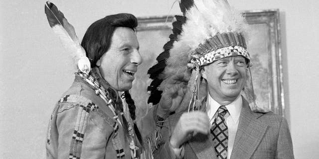 President Carter dons an Indian headdress as he chats with Iron Eyes Cody, the "concerned Indian," during a ceremony at the White House in 1978.