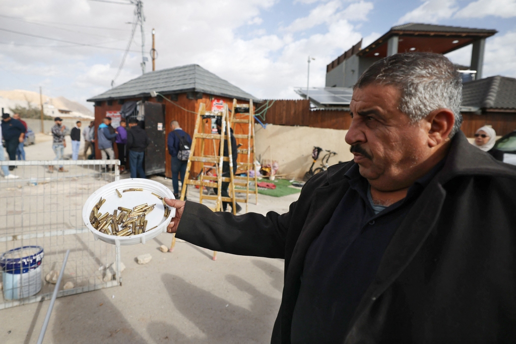 A man shows empty bullet shells in the aftermath of a gunfight at the scene of a raid by Israeli forces on an office where they said Palestinian militants were hiding in Jericho in the occupied West Bank on February 6, 2023