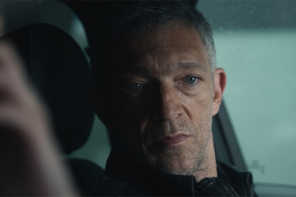 Vincent Cassel sitting in a car looking sinister. 
