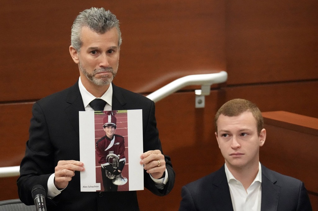 A picture of Max Schachter, with his son, Ryan, by his side, holds a photograph of his other son, Alex, just before giving his victim impact statement during the penalty phase of the trial of Nikolas Cruz.