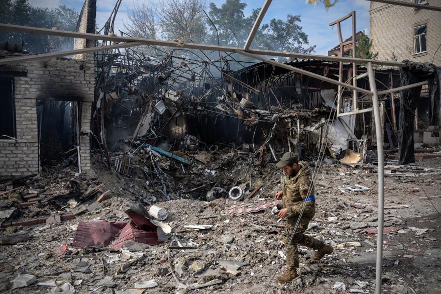 A soldier passes the crater where a Russian missile struck a shopping area.