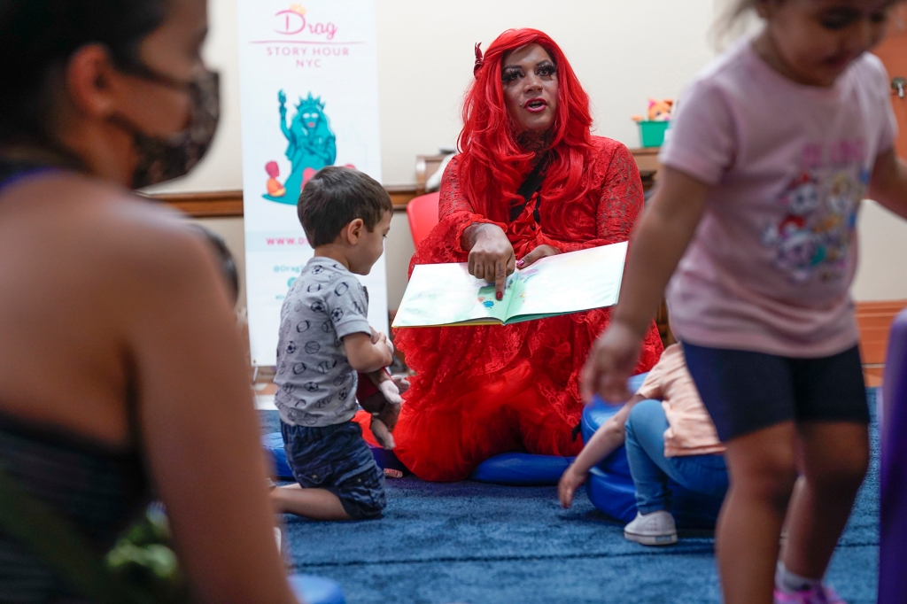 A drag queen who goes by the name Flame reads stories to children and their caretakers during a Drag Story Hour at a public library in New York.