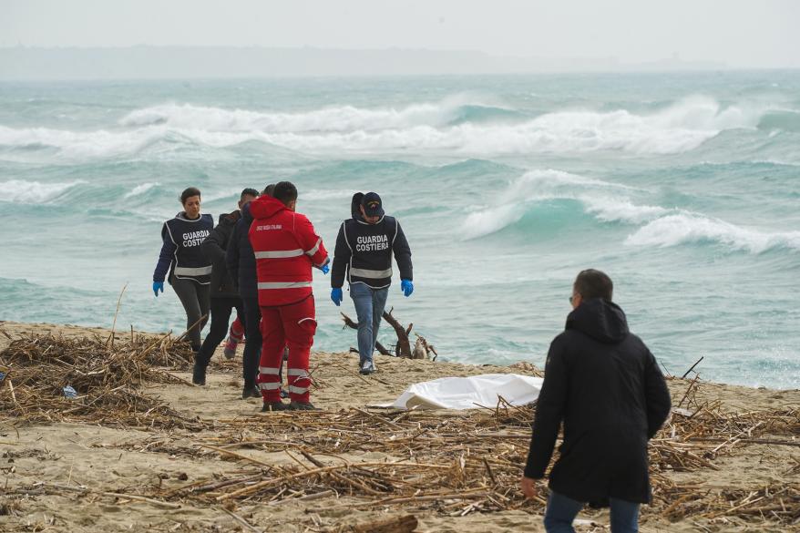 Agents of the Coast Guard, with volunteers from the Red Cross and Carabinieri try to recover the body of a migrant closed in a white bag,