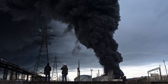 People watch as smoke rises in the air after shelling in Odessa, Ukraine, Sunday, April 3, 2022.