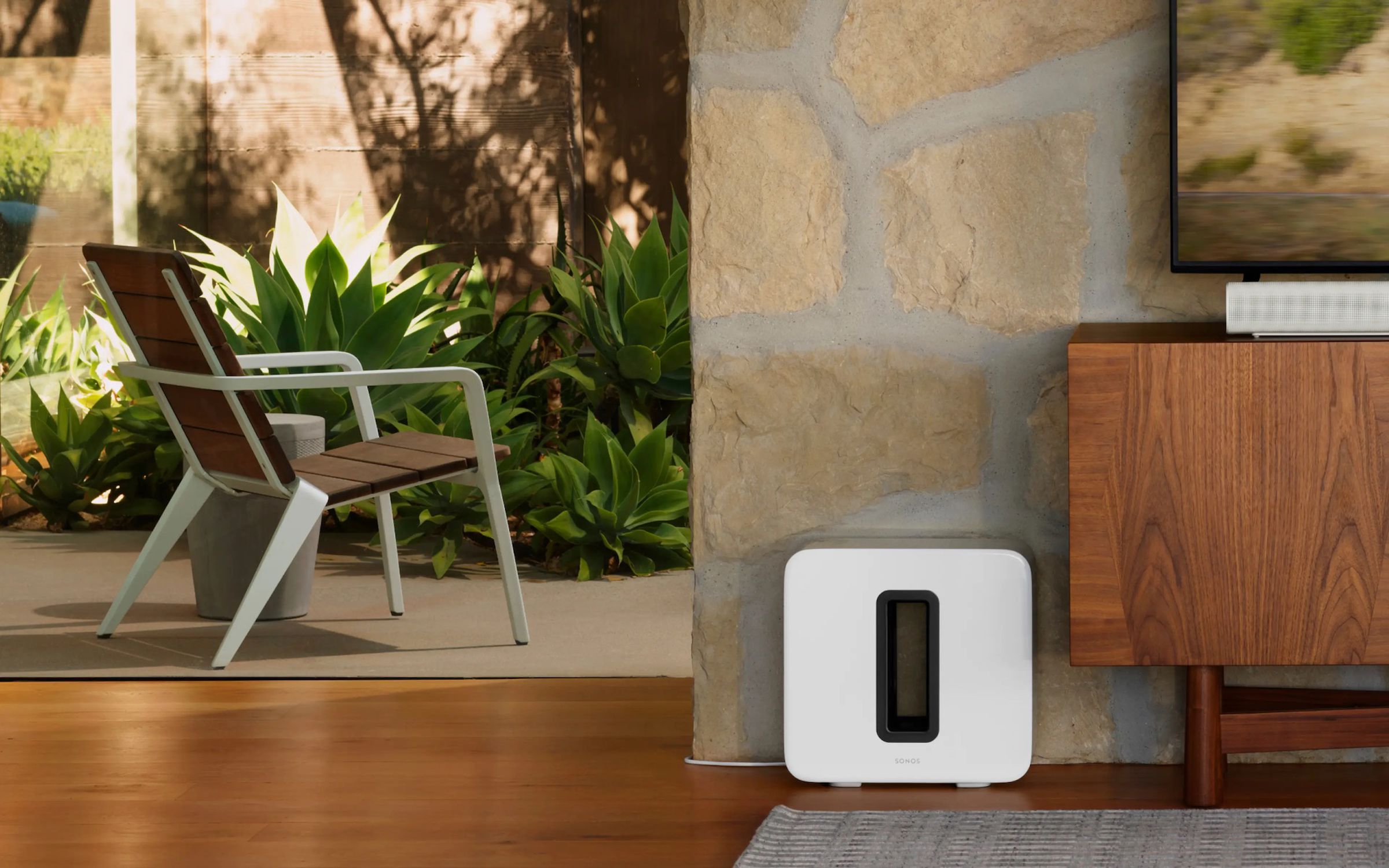 A photo of the white Sonos sub on a floor beside a cabinet.