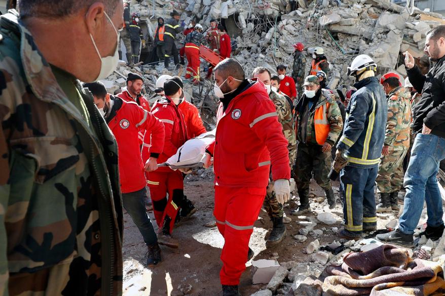 Rescue teams carry the body of a victim from a destroyed building after a devastating earthquake rocked Syria and Turkey, in the costal town of Jableh, Syria, Thursday, Feb. 9, 2023.