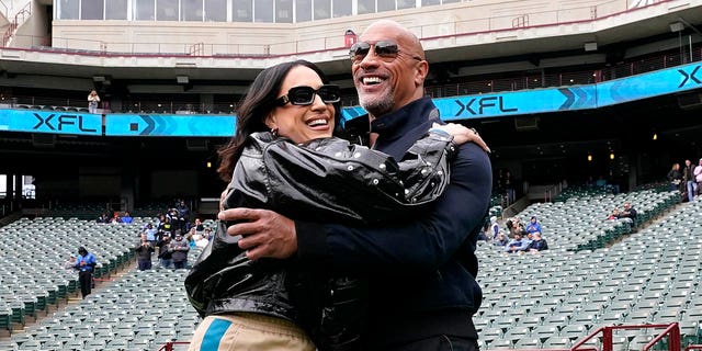 XFL owners Dwayne Johnson and Dany Garcia greet each other on the field before the game between the Arlington Renegades and the Vegas Vipers at Choctaw Stadium on February 18, 2023, in Arlington, Texas.