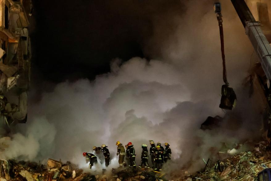 Emergency personnel work at the site where an apartment block was heavily damaged by a Russian missile strike.