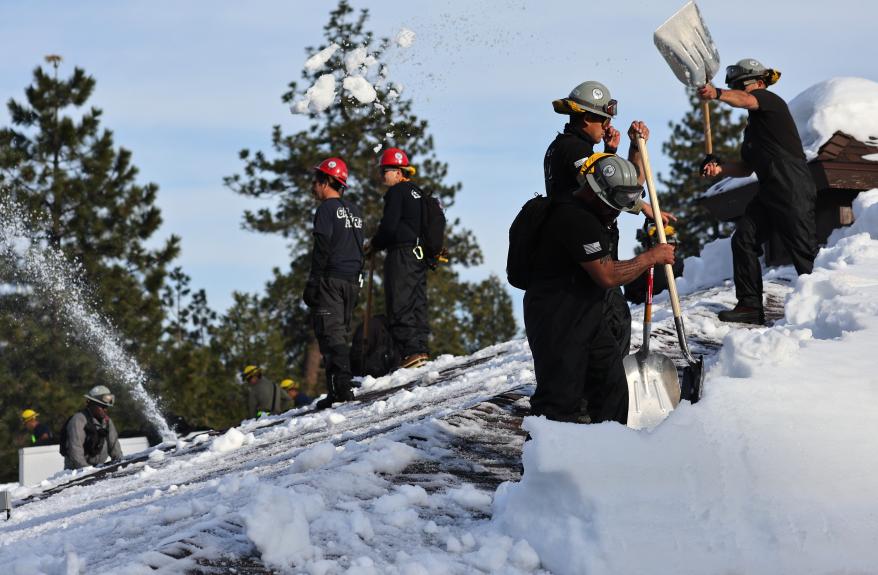 Members of the California Army National Guard Joint Task Force Rattlesnake shovel snow from a rooftop after a series of winter storms dropped more than 100 inches of snow in the San Bernardino Mountains March 8, 2023 in Crestline, Calif.