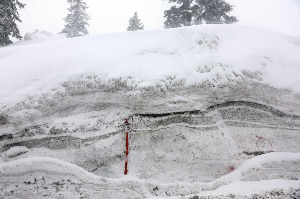 A "No Parking" sign pokes out of a snowbank in Mammoth Lakes, California after the region was once again hit by an atmospheric river event dropping several feet of snow. 