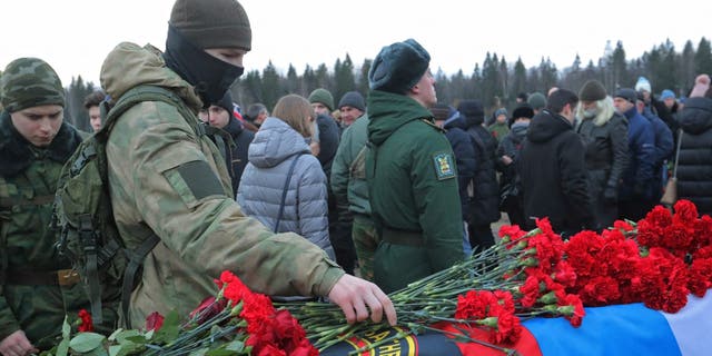 A man places flowers during the funeral of Dmitry Menshikov, a Wagner Group mercenary killed during the military conflict in Ukraine, in the Alley of Heroes at a cemetery in Saint Petersburg, Russia, Dec. 24, 2022.